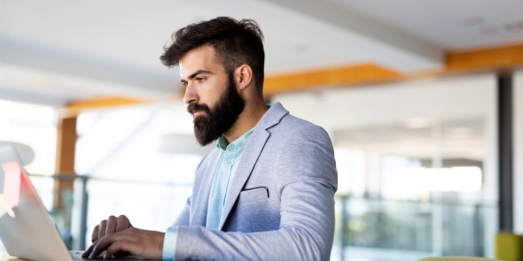 Young employee looking at computer monitor during working day in office